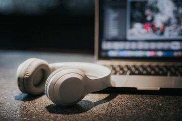 Obraz na płótnie Canvas White headphones and laptop on table in dark room.