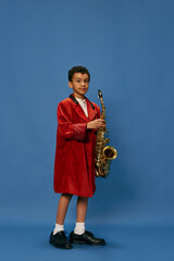 Portrait of cute little african boy wearing huge man's jacket and shoes like jazz man playing on...