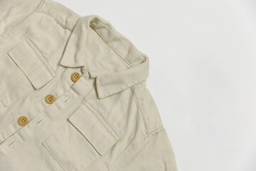 Part of a beige denim baby shirt with buttons for a boy or girl on a white background top view.