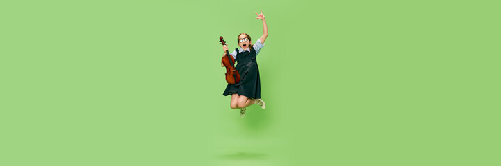 Cute little girl, talanted musician wearing huge mother's heels shoes jumping with violin, having...