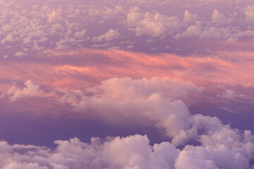 Looking down on pink clouds at sunrise from high elevation - obrazy, fototapety, plakaty