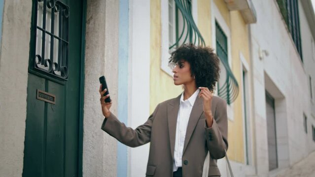 Girl walking holding smartphone. African american woman taking picture on phone.