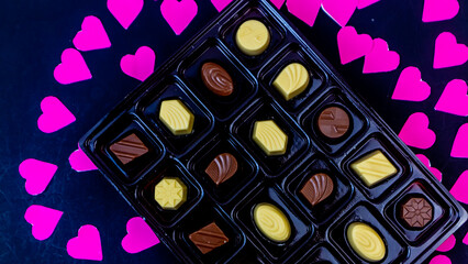 delicious chocolate surrounded by pink hearts on black background