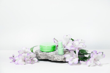 White cosmetics background. Cosmetic bottle containers with flowers plant . Blank label package for branding mock-up, with hard shadows. Natural organic beauty product concept.