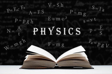 The study of physics, the science of the laws of nature. An open book, a textbook lies on the table. Physical formulas and signs on a black background.