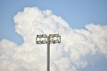 Iluminación de cancha deportiva acompañada de un cielo nublado de fondo.