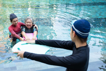 Young trainer helping senior woman in aqua aerobics and working out in the pool. old woman and...