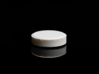 A single isolated pill or medicine tablet on black background