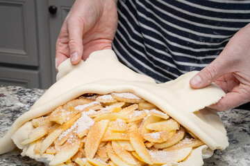 Man folds over the crust of an apple  pie he is making