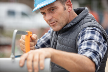 Fototapeta premium plumbing sawing plastic pipe on construction site