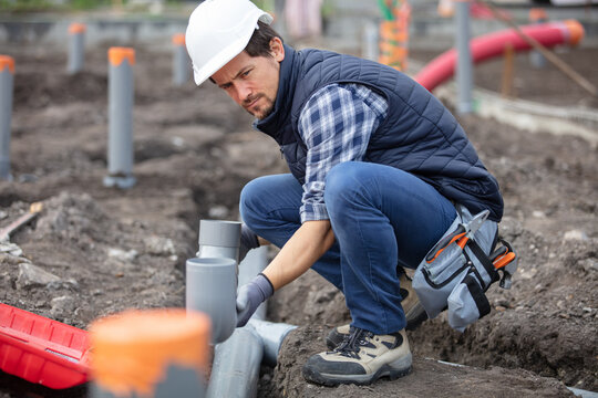 builder man installing pvc pipes outdoors