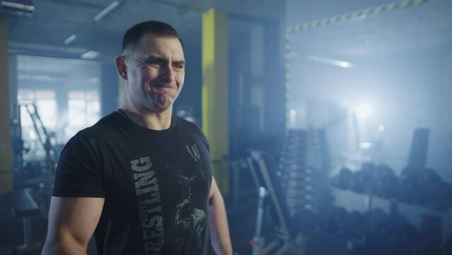 Caucasian male athlete trains in the gym with dumbbells. Bodybuilder swings his arms while lifting dumbbells. Sports training, workout and a healthy lifestyle.