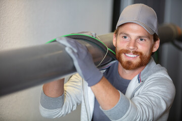 construction worker on site carrying pipe on shoulder