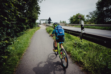 Fototapeta na wymiar Kleiner Junge auf einer Fahrradtour durch Niedersachsen überquert mit seinem Mountainbike eine Brücke über die Aller, Deutschland