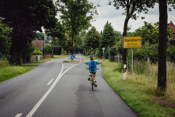 Kleiner Junge beim Ortsschild-Sprint während einer Fahrradtour, Niedersachsen, Deutschland