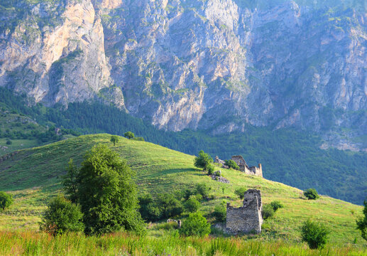 Beautiful mountain view - ruins of the ancient ingush ancestral complex Barkinhoy, green hill and barren rock at the background. Morning near Leimi village, Ingushetia, North Caucasus, Russia