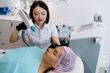 Female cosmetologist doing photo epilation procedure on face of woman
