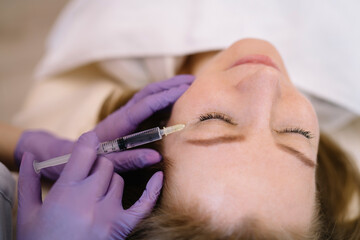 Woman getting beauty facial injection in salon