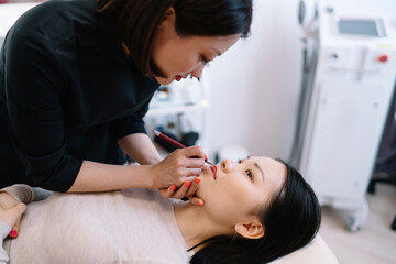 Obraz na płótnie Canvas Beauty specialist doing lip makeup to client