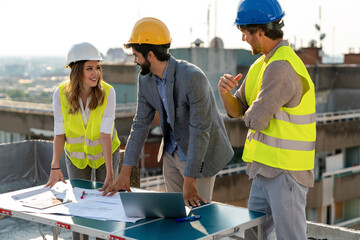 Construction concept. Engineers and architects working at construction site with blueprint
