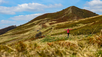 Obraz premium Beautiful fit happy girl in pink jacket enjoys hike in stunning colorful mountain scenery. Spring in the Bieszczady Mountains, Poland, Europe