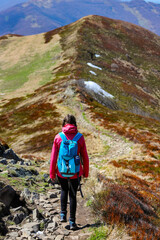 Obraz premium Beautiful fit happy girl in pink jacket enjoys hike in stunning colorful mountain scenery. Spring in the Bieszczady Mountains, Poland, Europe