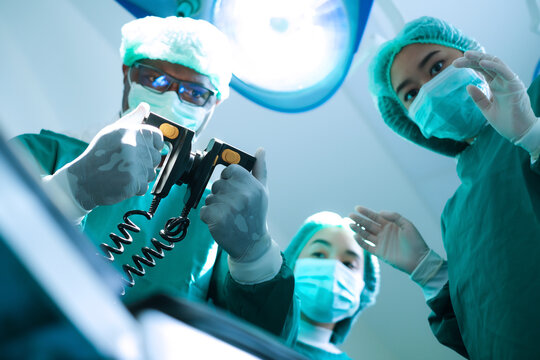 Doctor using defibrillator to patient at operating room in hospital.