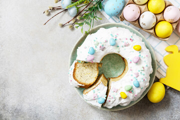 Happy Easter holidays, tasty dessert. Glazed easter lemon cake decorated with confectionery and mini chocolate eggs candy on gray stone background. View from above. Copy space.