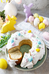 Glazed easter lemon cake decorated with confectionery and mini chocolate eggs candy on gray stone background. Happy Easter holidays, tasty dessert.