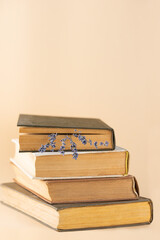 Stack of old books with lavender flowers on a beige background, education, learning, culture.