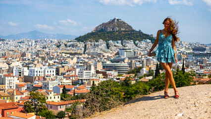 beautiful long hair tanned model standing on the hill with athens city in the backgroud; vacation in the capitol of greece, short dress woman