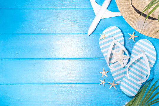 Bright sunny lighted summer vacation background, vacation and travel, beach accessories, swim suit, hat, flip flops, photo camera, sea star and shells on high-colored blue wooden background top view