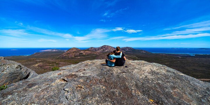 romantic hugging couple sitting on the top of frenchman peak in western australia; couple in love on the top of the mountain near esperance, cape le grand national park