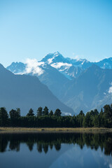 Naklejka premium Spiegelsee, Lake Matheson, in Neuseeland mit Bäumen, wolken, Gletscher und Mt Cook an der Westküste auf einem Roadtrip.