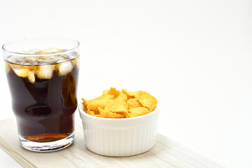 Tiras de maíz y bebida de cola sobre fondo blanco, espacio para texto al lado derecho.