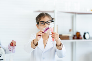 Arab girl wearing glasses in the role of a scientist is paying attention to the color in the test tube in the science classroom. elementary school chemistry science experiment