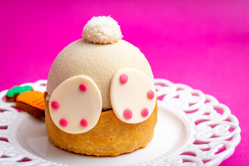 Easter bunny tail and back paws on green sugar paste on a white plate and pink background
