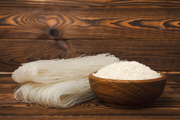 Funchoza.Dried raw rice noodles and rice on a brown wooden background.Noodles with rice flour. Diet food. Healthy food. Place for text. Place for copying.