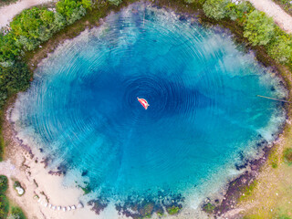 girl in a white bikini swims on a mattress in the spring of the river cetina in croatia, a unique deep river spring with crystal clear water