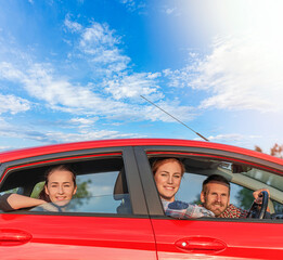 A company of young happy people in a red car.