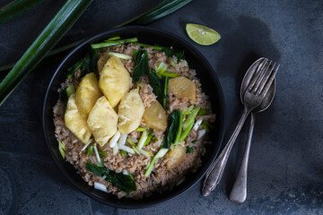 Pineapple fried rice has minced pork and vegetable in plate on stone table.