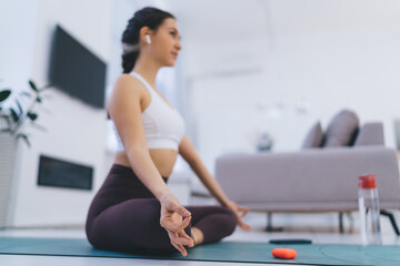 Slim woman doing yoga on mat in living room