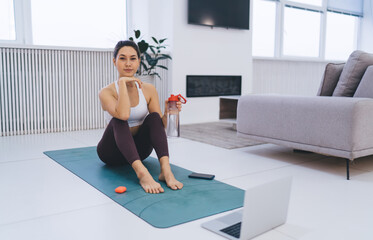 Slim woman resting on mat with water at home