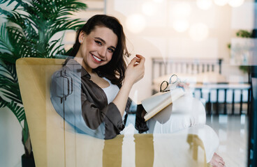 Cheerful woman sitting in modern bedroom with book