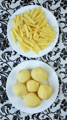 Raw french fries. Raw potatoes cut into strips, prepared for french fries, isolated on a white plate. Peeled potatoes. Cooking, raw vegetables