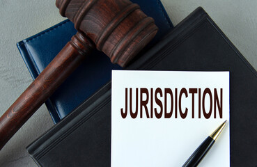 JURISDICTION - word on a white sheet with leather notebooks, a judge's hammer and a pen