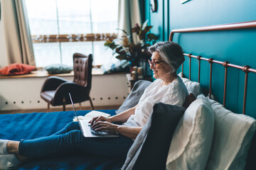 Senior woman working on laptop in bedroom