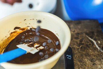 Mixing, melting chocolate callets in a bowl on a kitchen scale. High quality photo