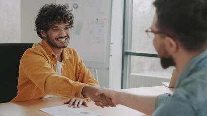 Handshake of business partners in the office in casual. Successful deal of young indian businessman