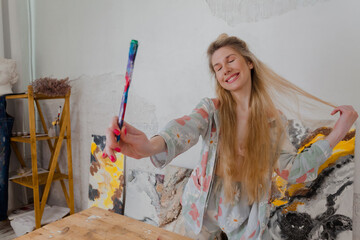 Talented happy Female Artist smiling and holding a brush. Colorful, Emotional, Sensual Painter Creating Abstract Modern Art. Creative Expression concept.